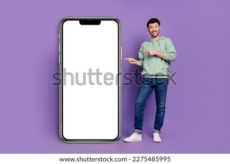 Full size photo of handsome young man pointing excited device empty screen dressed stylish khaki outfit isolated on purple color background
