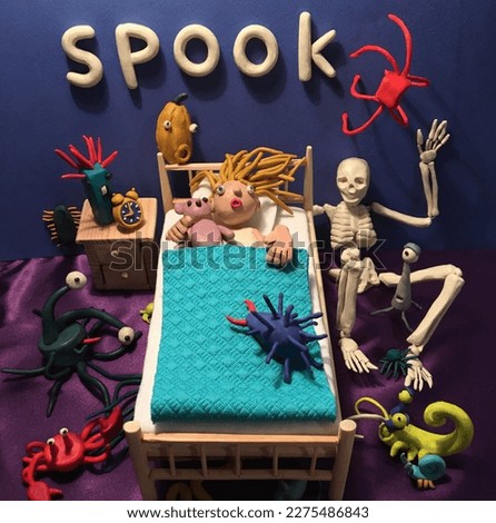  A little plasticine girl lies on a wooden bed,  surrounded by a funny pumpkin, monsters, skeleton and she's a little scared. With volumetric lettering Spook. Halloween mood. Halloween picture. 