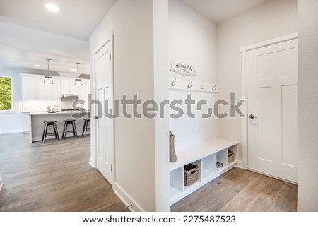 Laundry room and mud room waiting area coat rack hooks baskets shoes washing machine dryer cabinets cupboards interior home Royalty-Free Stock Photo #2275487523