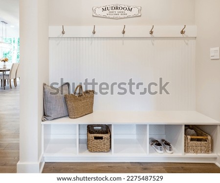 Laundry room and mud room waiting area coat rack hooks baskets shoes washing machine dryer cabinets cupboards interior home Royalty-Free Stock Photo #2275487529