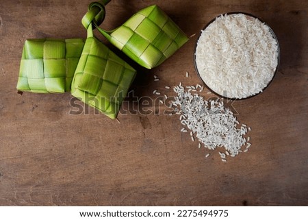 Close up view of Ketupat and rice, an Indonesian traditional cuisine very popular during Hari Raya Idul Fitri. Ketupat is a natural rice casing made from young coconut leaves for cooking rice. Royalty-Free Stock Photo #2275494975