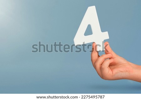 number four in hand. Hand holding white number 4 on blue background with copy space. Concept with number four. Birthday 4 years, fourth grade, four day work week Royalty-Free Stock Photo #2275495787