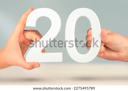 Number twenty in hand. Hand holding white number 20 on blurred background with copy space. Concept with number twenty. 20 percent, birthday 20 years Royalty-Free Stock Photo #2275495789