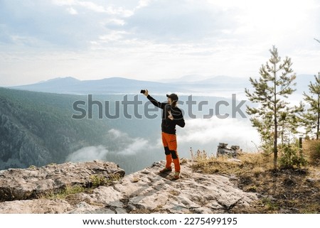 The blogger shoots content, traveling through the mountains, photos on the phone, selfie yourself, a rocky cliff, face photography. High quality photo
