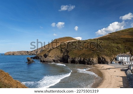 Llangrannog Beach with the distinctive sea stack Carreg Bica Rock in vew. Llangrannog is a small, coastal village and seaside resort in Ceredigion, viewed here from the Wales Coast Path. Royalty-Free Stock Photo #2275501319