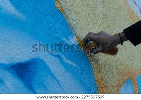 someone handing a spray can and painting a colorful graffito on a wall Royalty-Free Stock Photo #2275507529