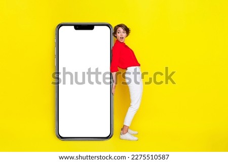 Full body photo of impressed lady look interested empty space big telephone screen isolated on yellow color background