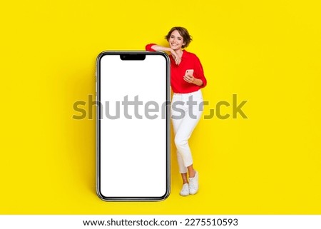 Full size portrait of cheerful nice girl hold telephone empty space poster isolated on yellow color background