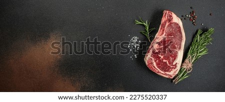 New York steak with salt and rosemary, raw marbled beef strip loin steak on a dark background, Long banner format. top view, Royalty-Free Stock Photo #2275520337