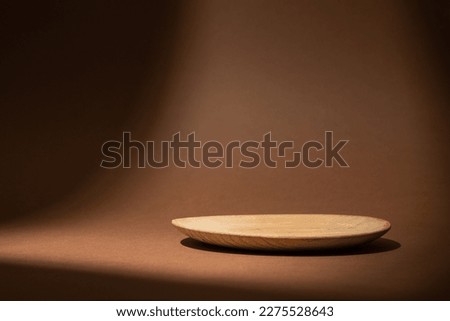 Round wooden tray for food, products or cosmetics against dark brown background. Front view.

