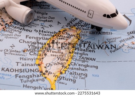 Close up detail of a miniature passenger airplane on a colorful map focusing on Taiwan through selective focus, background blur