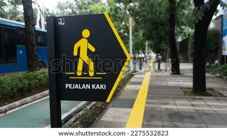 Pedestrian sign in yellow and black background.
