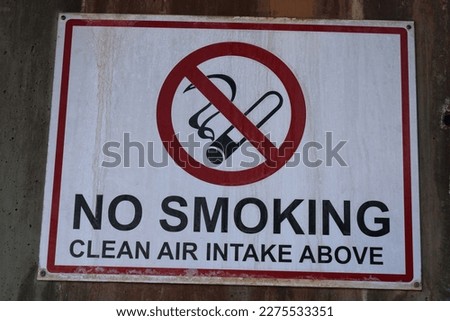 An old "No Smoking" sign on a concrete wall.