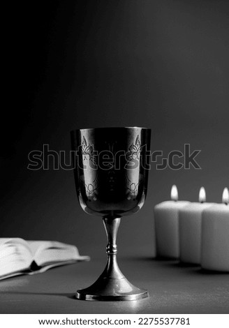christian chalice with open bible and candles in the background. black and white photography