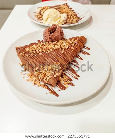 The traditional French dessert and popular street food, sweet crepes with cream and chocolate, are captured in a close-up shot. This is a typical delicacy of France in Europe. Royalty-Free Stock Photo #2275551791