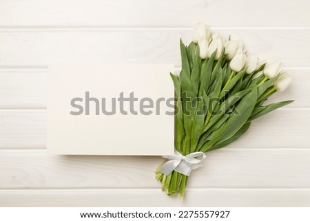 Greeting card mockup with tulips on color background, top view