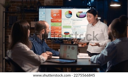 Project manager presentation, asian company employee explaining analytics research results in business meeting, showing statistics diagrams on digital board. Marketing revenue report visualization