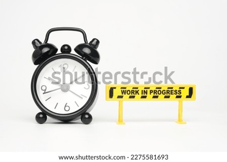 A picture of alarm clock with work in progress sign.