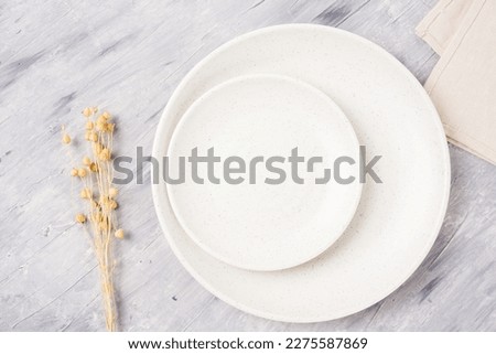 white plate mockup and dried flowers. gray cement pattern background. top view.