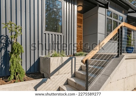 Front door entry exterior of a contemporary home with grey metal siding black entrance and cedar siding Royalty-Free Stock Photo #2275589277
