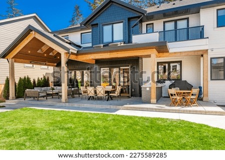 classic home exterior with cement tile patio deck stone entry wide front door patio with chairs and a fire pit area with trees and bbq seating dining on a bright sunny colorful day blue sky 