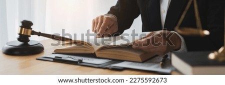 Asian female lawyer, law adviser, businesswoman sitting and reading with finger pointing at legal code information. Business agreement on book working with scales and hammer in office.