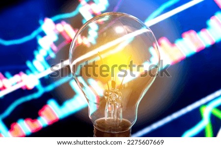 Energy stock concept.Bulb light with index stock market graph background.