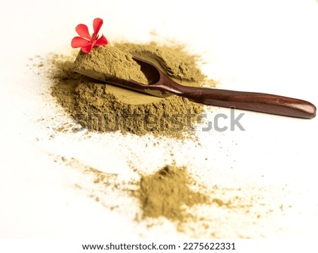 Natural henna powder, wooden spoon, red flower on a white background close-up
