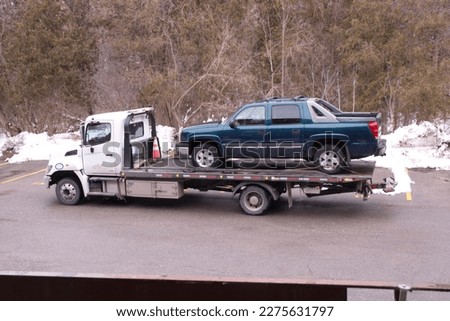 Showing a  vehicle loaded onto a modern Flatbed Tow Truck in winter with flashing lights.. For  business with advertisement space. Royalty-Free Stock Photo #2275631797