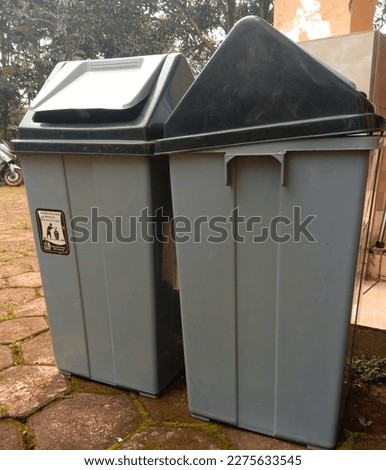 Two plastic trash cans on the terrace of a house