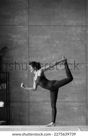 black and white photo. dancer working out indoors.side view full length photo.flexibility, grace, gracefullness