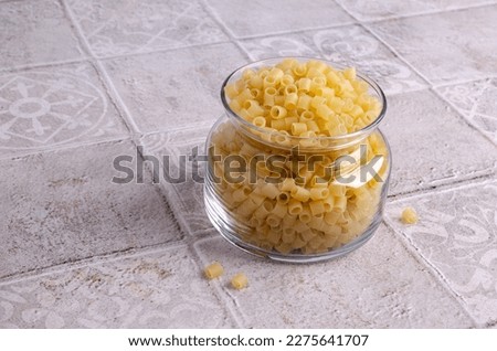Traditional Italian dry pasta in a glass jar on a light background. Copy space. Selective focus.