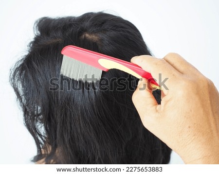 Mother using nit comb on her daughter's hair of anti lice treatment. Lice removal product concept. Closeup photo, blurred.