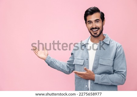 Fashion portrait of a brunette man with a beard happiness victory raised his hands with his fist up on a pink background in a white T-shirt smile and joyful emotion on his face, copy space Royalty-Free Stock Photo #2275658977