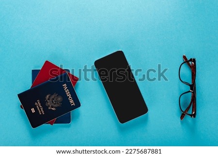 American passport, glasses and smartphone for booking flight tickets via mobile app