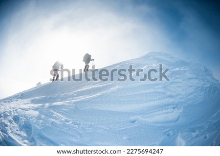 climbing a snow-covered mountain, two women in winter trekking, climbers climb to the top of the mountain in winter Royalty-Free Stock Photo #2275694247