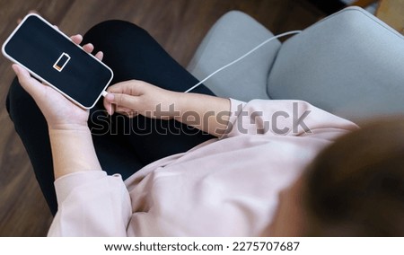 Woman hands Charging mobile phone battery with low battery. plugging a charger in a smart phone  with energy bank powerbank power charger Modern lifestyle energy technology concept.