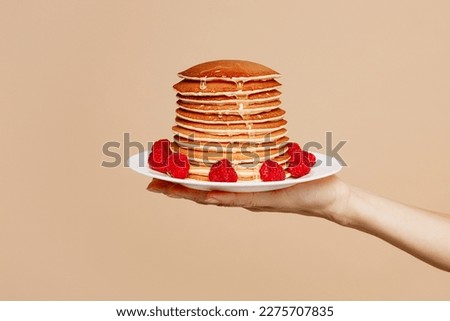 Close up cropped female hold in hand tasty yummy stacke of pancakes with raspberries isolated on pastel plain light blue color wall background studio. Cook food concept. Copy space advertising mock up Royalty-Free Stock Photo #2275707835