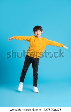 full body image of asian boy posing on blue background Royalty-Free Stock Photo #2275708395