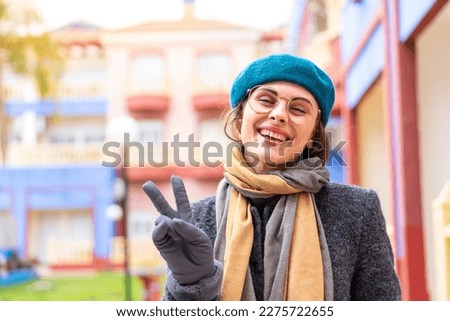 Brunette woman at outdoors With glasses and doing OK sign