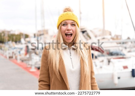 Young pretty blonde woman wearing winter jacket at outdoors with surprise facial expression