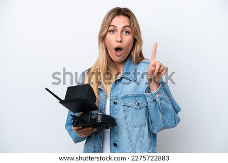 Young Uruguayan woman holding a drone remote control isolated on white background intending to realizes the solution while lifting a finger up
