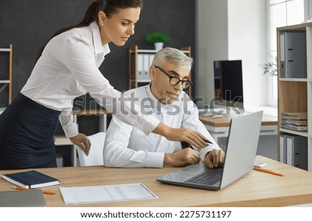 Young woman director views the project of the employee on the laptop screen, shows the inaccuracies of the project. A beautiful business woman shows her middle-aged employee on the laptop screen. Royalty-Free Stock Photo #2275731197