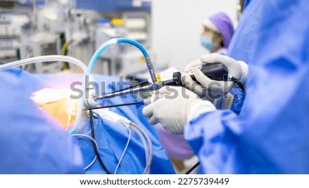 Doctor or Surgeon did laparoscopic or endoscopic minimal invasive surgery inside operating room in hospital.People hold medical instrument arthroscopic orthopedic surgery in blue uniform with light. Royalty-Free Stock Photo #2275739449