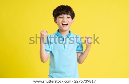 portrait of an asian boy posing on a yellow background Royalty-Free Stock Photo #2275739817