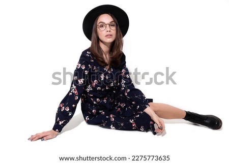 Studio portrait, a woman wearing a gorgeous dress and oversized hat exudes glamour and grace. Her confident pose and serene expression convey a sense of inner beauty and confidence