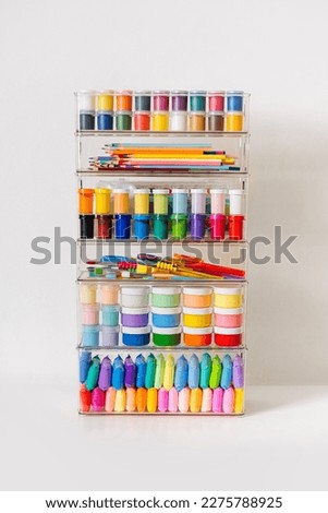 Paints, pencils, plasticine and various material for creativity and kids art activity in containers on shelves. Stationery and supplies for drawing and craft. Organizing and storage craft room. Royalty-Free Stock Photo #2275788925