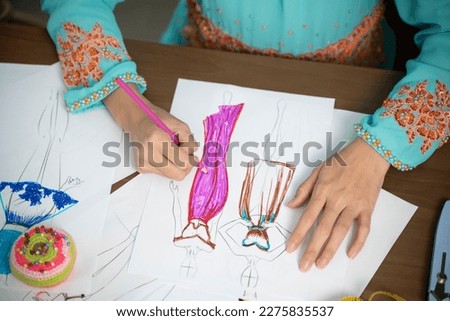 Islam woman in design home sitting at desk sketching fashion design.