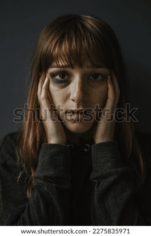 Vertical portrait picture of beaten woman standing in front of a dark wall - Stop violence against women concept Royalty-Free Stock Photo #2275835971