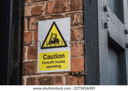 Caution fork-lift trucks operating sign on brick wall background, safety and information concept illustration.